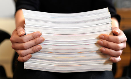 A close up view of female hands holding up a stack of paper while sitting