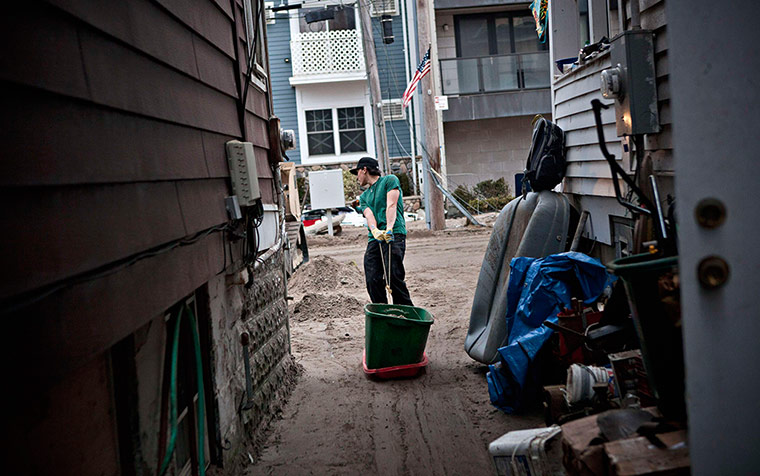 Hurricane Sandy clean-up: A volunteer drags a bucket of sand from a backyard in Rockaway Beach