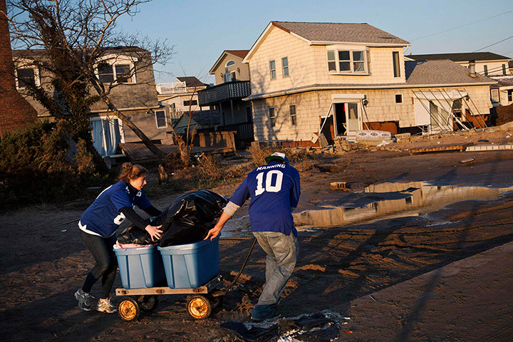 Hurricane Sandy clean-up: A man and woman wheel their belongings from their house in Breezy Point