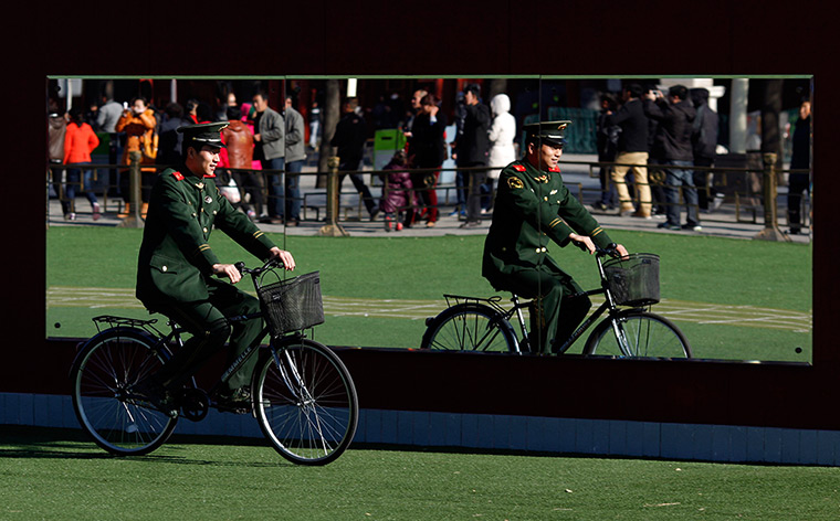 Carlos Barria China: A paramilitary policeman is reflected in a mirror as he rides a bicycle 