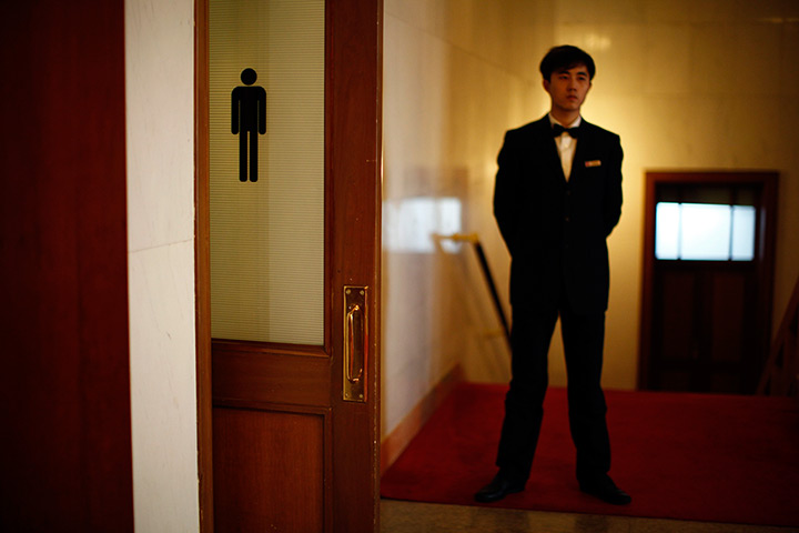 Carlos Barria China: A security officer stands next to the door of a bathroom