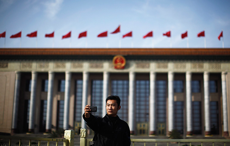 Carlos Barria China: A man takes a picture of himself in front of the Great Hall of the People
