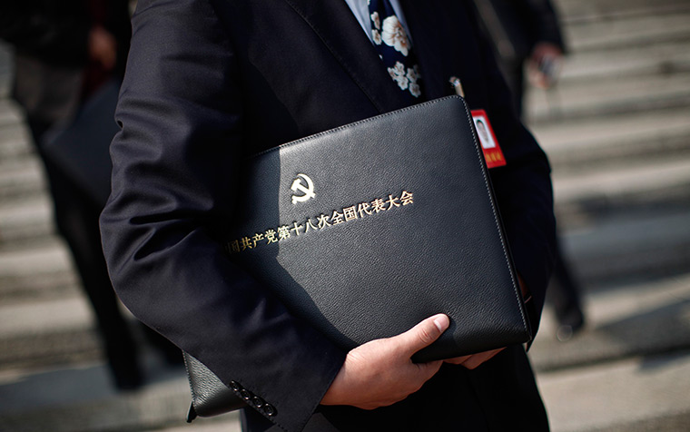 Carlos Barria China: A delegate holds a meeting bag with an emblem for the CPC