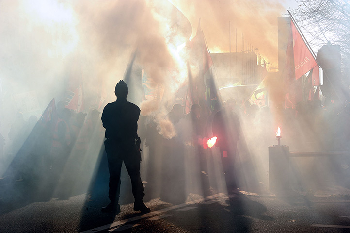 Euro protests: Lille, France: A police officer watches a man holding a flare