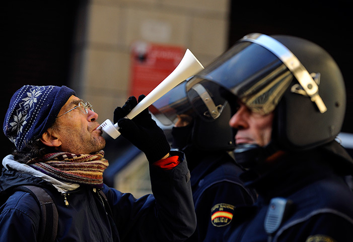Euro protests: Pamplona, Spain: A demonstrator blows a horn in front of riot police