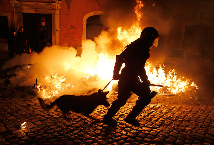 Europe protests: A riot policeman runs past a fire in Lisbon, Portugal