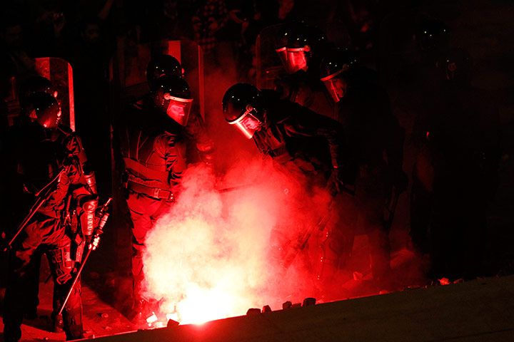 Europe protests: A flare illuminates policemen during clashes with protesters in Lisbon