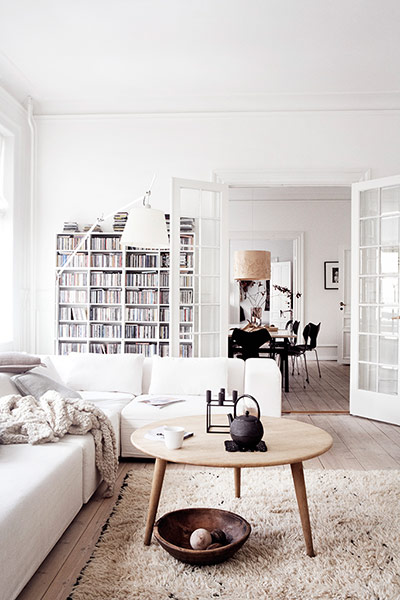 Homes: Danish: the living room with a coffee table and bookshelves in the background