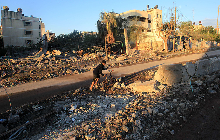 Strikes update: A Palestinian boy pushes his bycicle through the rubble