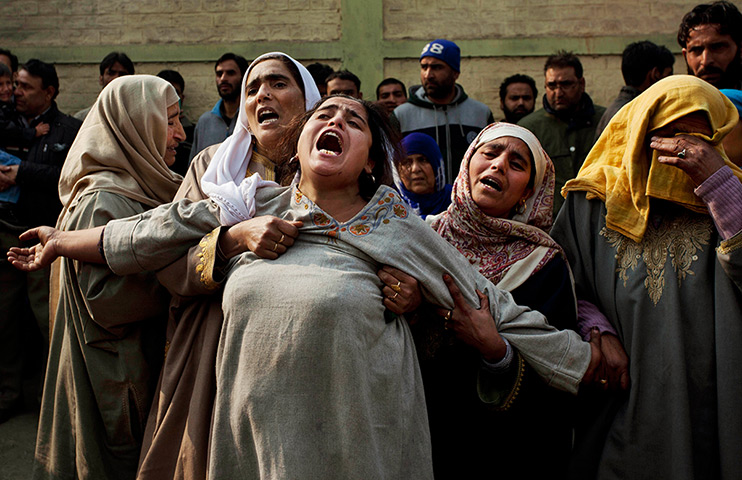 24 hours in pictures: Kashmiri Muslim women comfort a wailing relative of Mushtaq Ahmed
