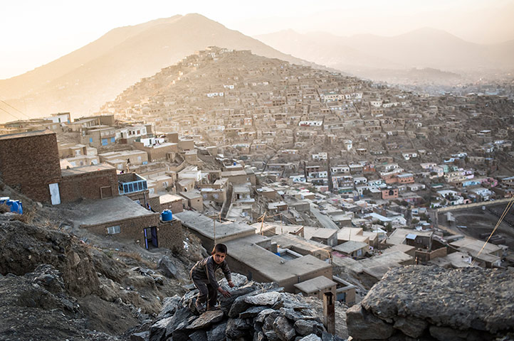 20 Photos: An Afghan boy climbs a rock fence in Kabul, Afghanistan