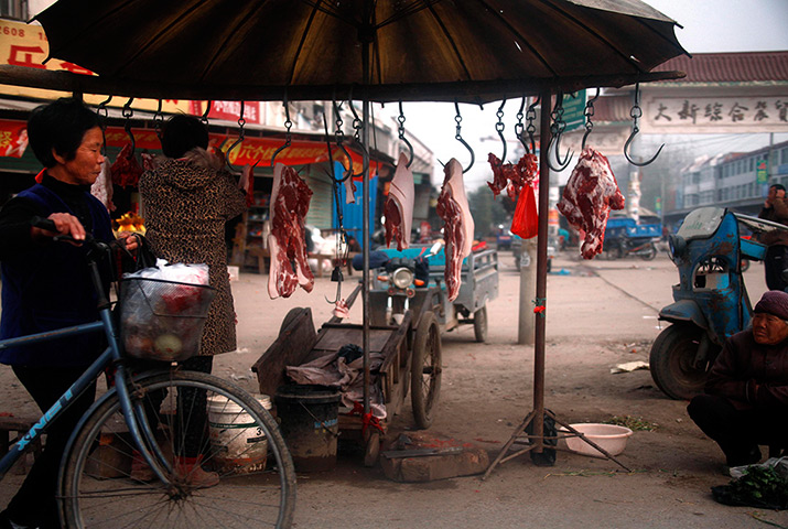 24 hours: Tianying, China: A woman passes a stall selling pork at a street market