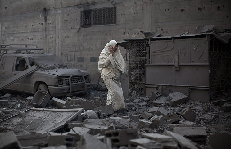 Gaza conflict: A women walks through the remains of a house