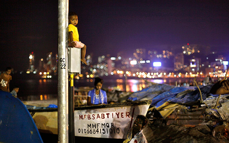 24 hours: Mumbai, India: A young Indian boy sits on an electric pole