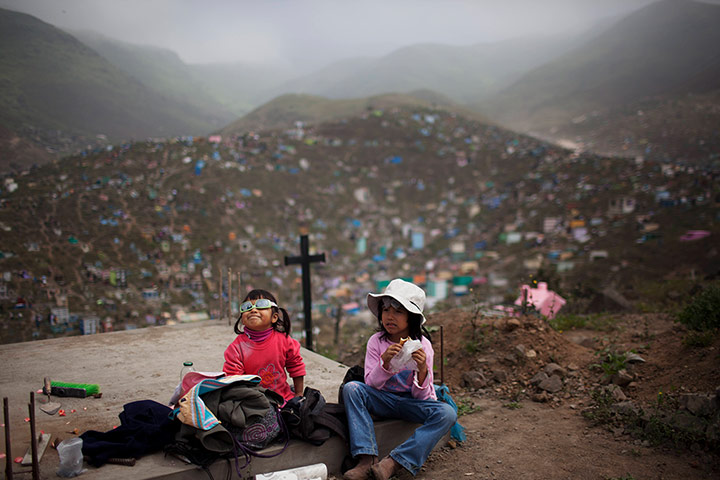 24 hours: Lima, Peru: Velentina Rojas, 5, and her sister Valeria, 2, rest on a tomb