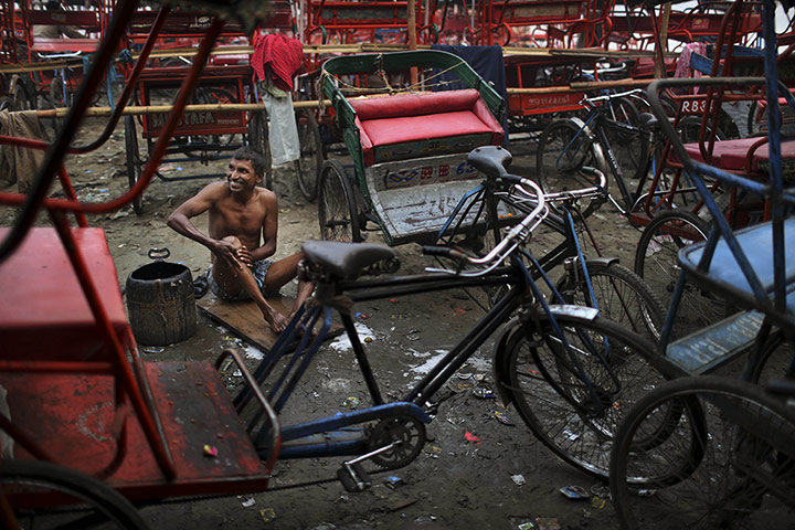 24 hours: New Delhi, India: An Indian bicycle rickshaw driver bathes before work