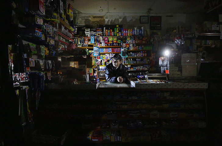 Superstorm sandy supplies: Park Choul waits behind the counter in his deli lit by flashlights