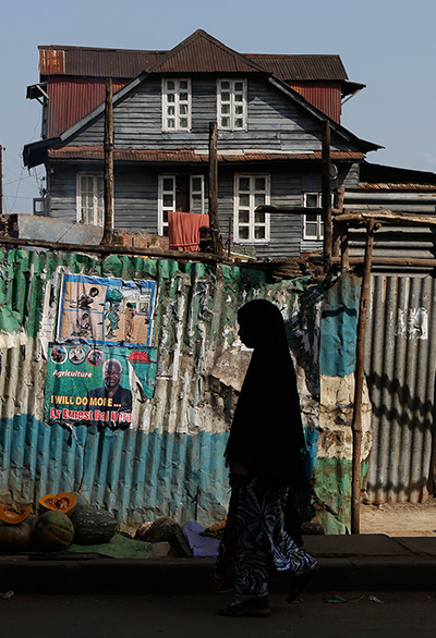 24 hours: Freetown, Sierra Leone: A conservative Muslim woman walks past posters