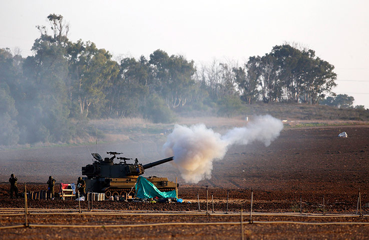 Israel Gaza : Israeli soldiers stand near a mobile artillery unit as it fires a shell