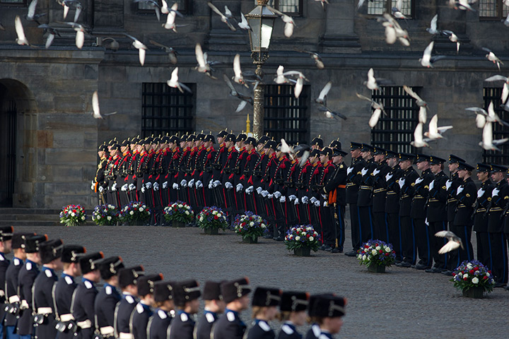 24 hours: Amsterdam, Netherlands: Pigeons fly overhead over the honour guard