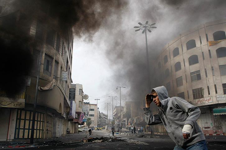 24 hours: Hebron, West Bank: A Palestinian youth looks at Israeli troops 