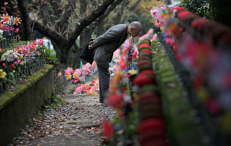 24 hours: Tokyo, Japan: A man looks at a line of statues of Ksitigarbha