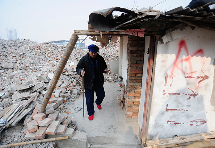 China demolition: Cao Wenxia, 75, the owner of a nail house, walks out of his house in Hefei