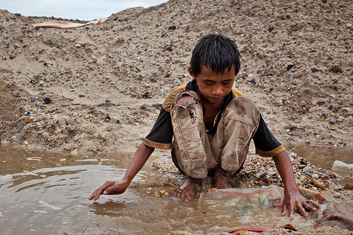 Tin Mining: Febri Andika, a child tin miner, searching for tin ore in Belo Laut Village