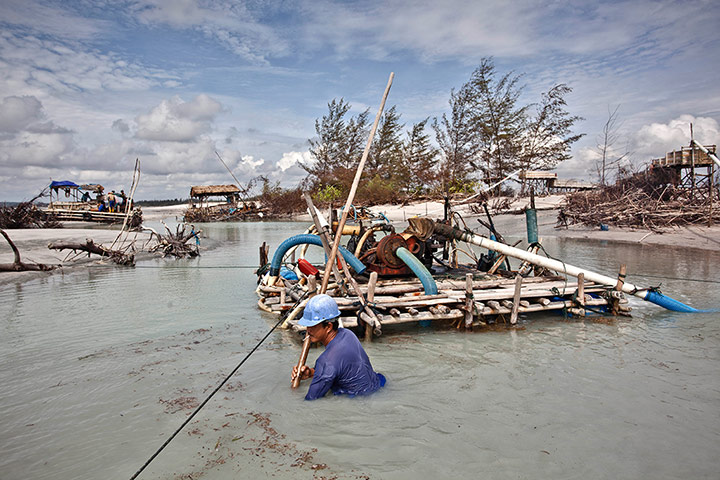 Tin Mining: Edi, a sea tin miner, uses a bamboo raft to dredge for tin ore