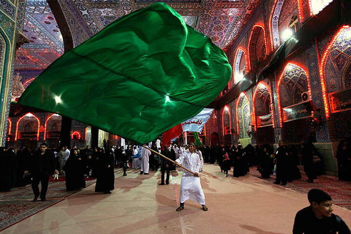 24 hours: A Shiite Muslim worshipper waves a green flag