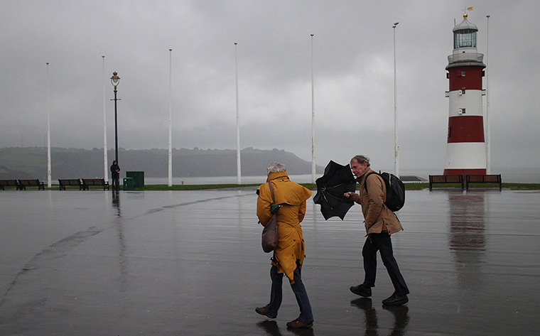 Autumn weather: People walk along the Hoe, Plymouth, in heavy rain and high winds 