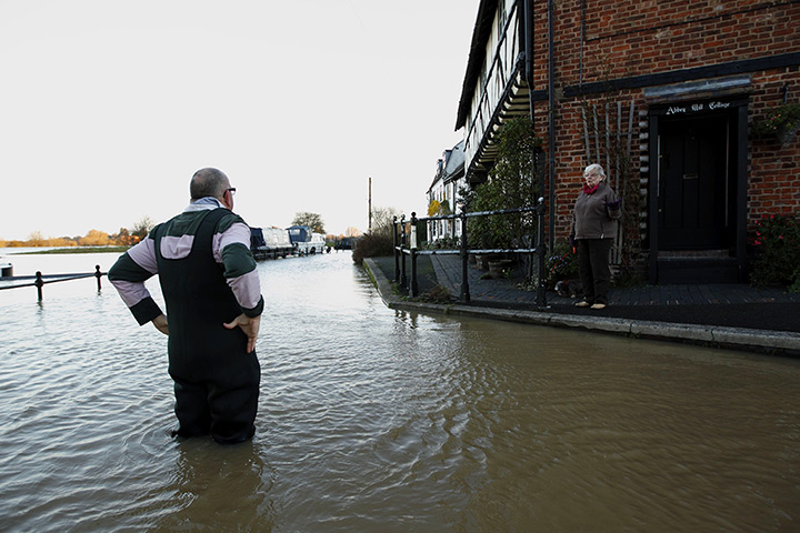 Autumn weather: A man speaks with a passing woman as he stands in floodwaters in Tewkesbury