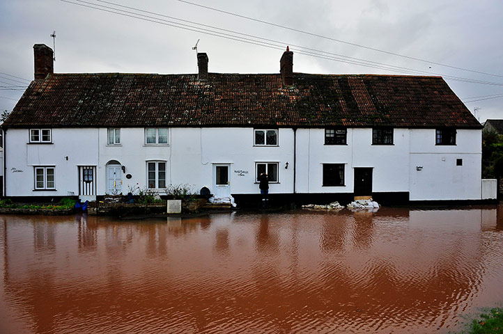 UK flooding: A girl looks through the window of a flooded cottage on Cheats Road