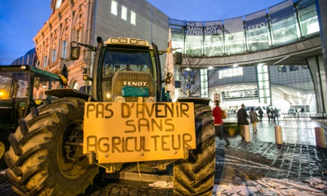 People walk past a tractor with a sign reading '' no future without farmer'' in front of the EU Parliament at Place du Luxembourg, on the second day of a protest against falling milk prices in Europe, on November 27, 2012 in Brussels. 