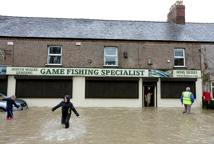 Residents rescued floods: Residents walk along a flooded street in St Asaph