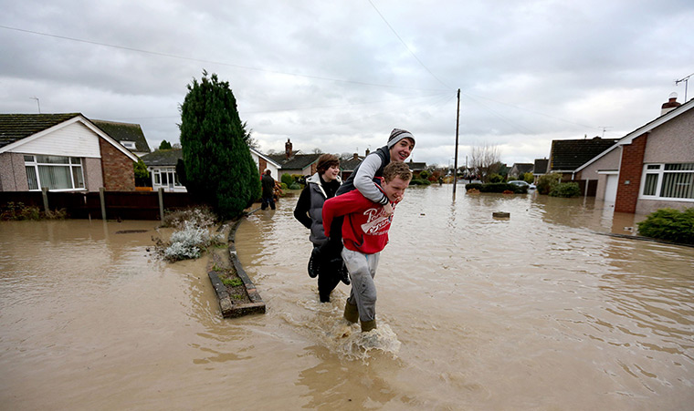 Residents rescued floods: Residents of St Asaph, Denbighshire, North Wales wade through flood waters