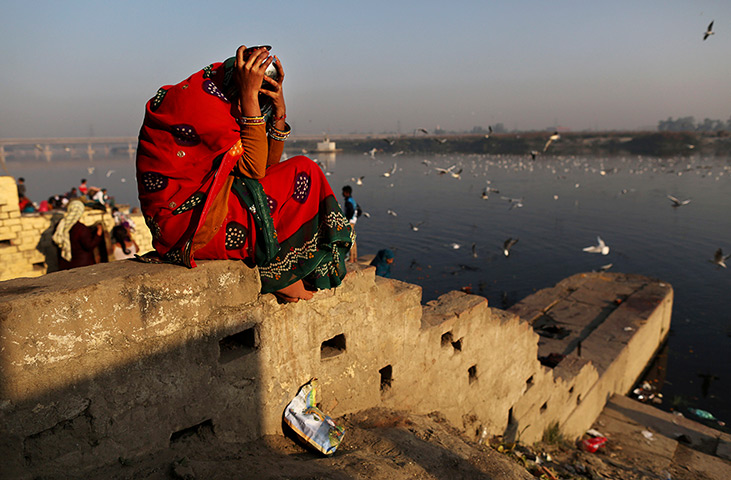 24hours in pictures: A Hindu devotee shields herself sitting on the banks of the Yamuna River