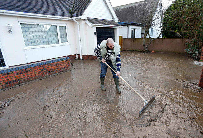 Floods clear-up: Tom Wynne sweeps muddy sediment off the drive of a home in St Asaph