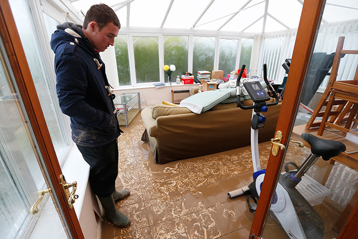 Floods clear-up: James Evans looks at muddy sediment in his home in St Asaph