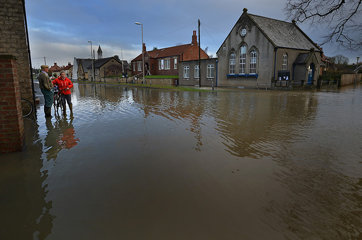 Floods clear-up: People stand on the edge of a flooded street in Old Malton