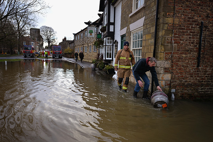 Floods clear-up: A man rolls a barrel through water in Old Malton