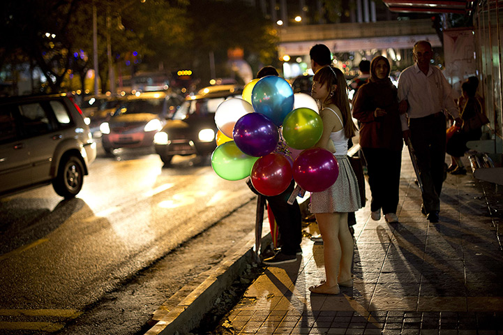 24 hours in pictures: A girl holds a bunch of balloons as she waits at a bus stop