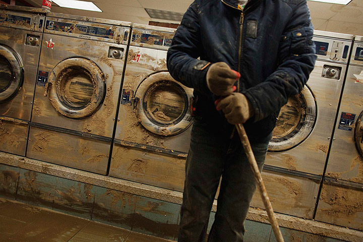 24 hours: Eddie Liu cleans up a launderette in New York, USA, after flooding caused by superstorm Sandy