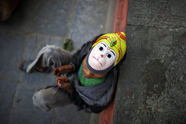 24 hours: A street child in Kathmandu, Nepal, wears a mask of the Hindu monkey god, Hanuman