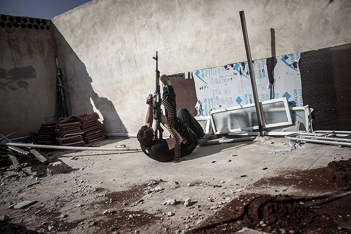 Twenty Photos: A rebel fighter fires a gun at an army jet in Aleppo