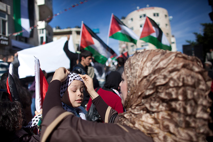 24 hours in pictures: A Palestinian woman adjusts a child's headwear during a rally 