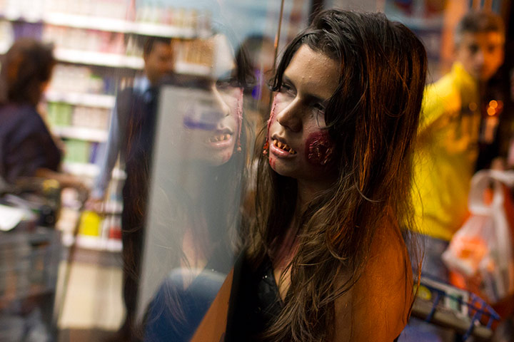 Zombie walk: A girl dressed as a zombie looks into a shop window