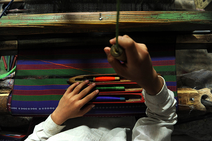 24 hours in pictures: A silk weaver makes a shwal on a loom in herat