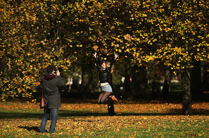 UK weather: Green Park, London: A woman throws leaves in the air