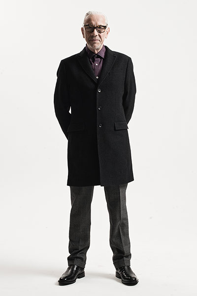 All Ages: Tailoring: Model wears black overcoat with purple shirt and grey suit trousers
